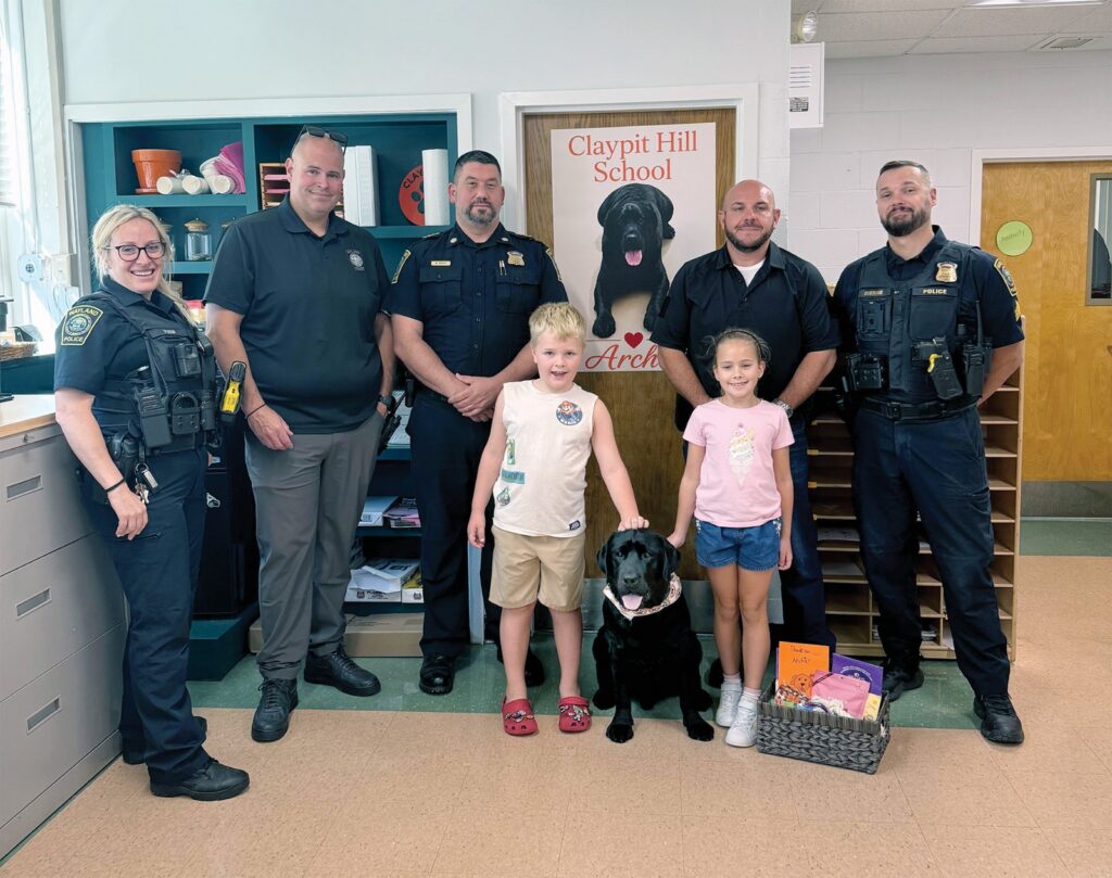 Wayland first responders and their four-legged helper visited the Claypit Hill School. Left to right: Officer Rachel Pugh, School Resource Officer Shane Bowles, Acting Chief Mark Hebert, Theo Burns, Archie, Hélène Genofre, Detective Sgt. Tyler Castagno, and Sgt. Christopher Custodie.