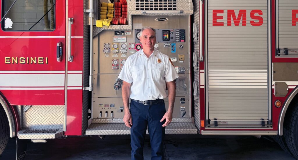 Wayland Fire Chief Neil McPherson in front of one of the town’s fire trucks. (Photo by Ellie Brogan)
