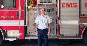Wayland Fire Chief Neil McPherson in front of one of the town’s fire trucks. (Photo by Ellie Brogan)